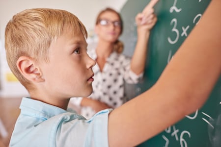 Third grader at the chalkboard as the teacher points out a multiplication problem