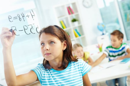 Fourth grader holding up an equation card in class