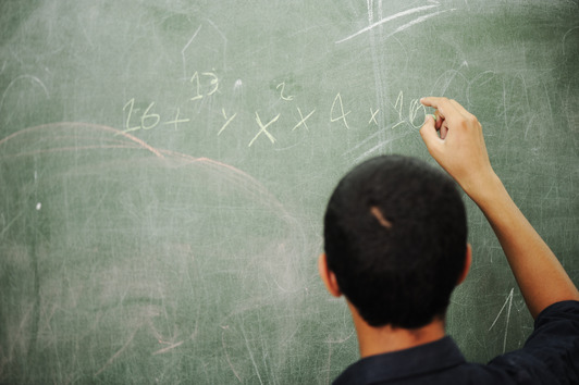 First grader working on addition at the classroom chalkboard