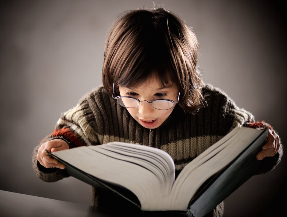 Young boy reading a big book and sounding out words