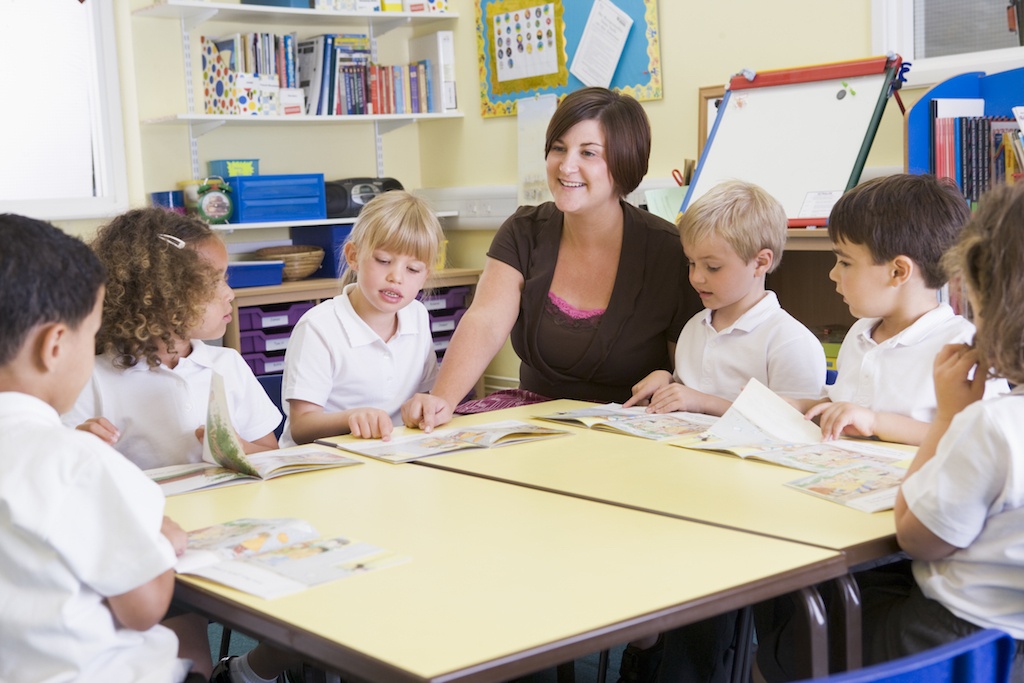 Teacher reading aloud with young students to practice letter sounds