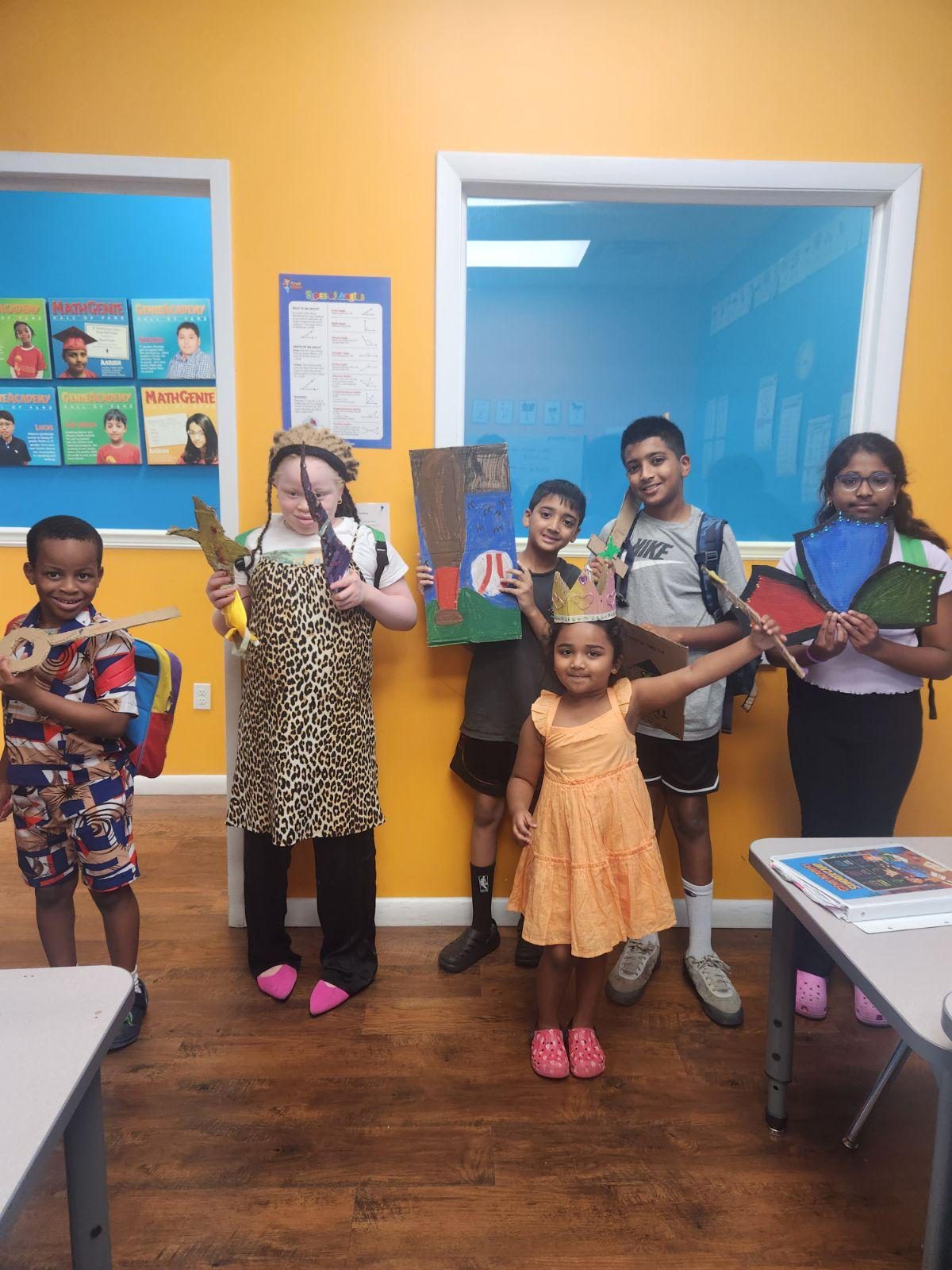 Genie Academy summer campers showing off the cardboard crowns, shields and creations they built during a camp workshop