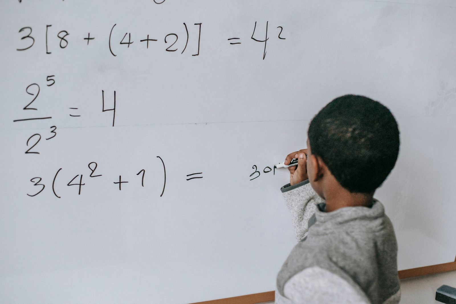 Student at a whiteboard working through exponent and order-of-operations problems