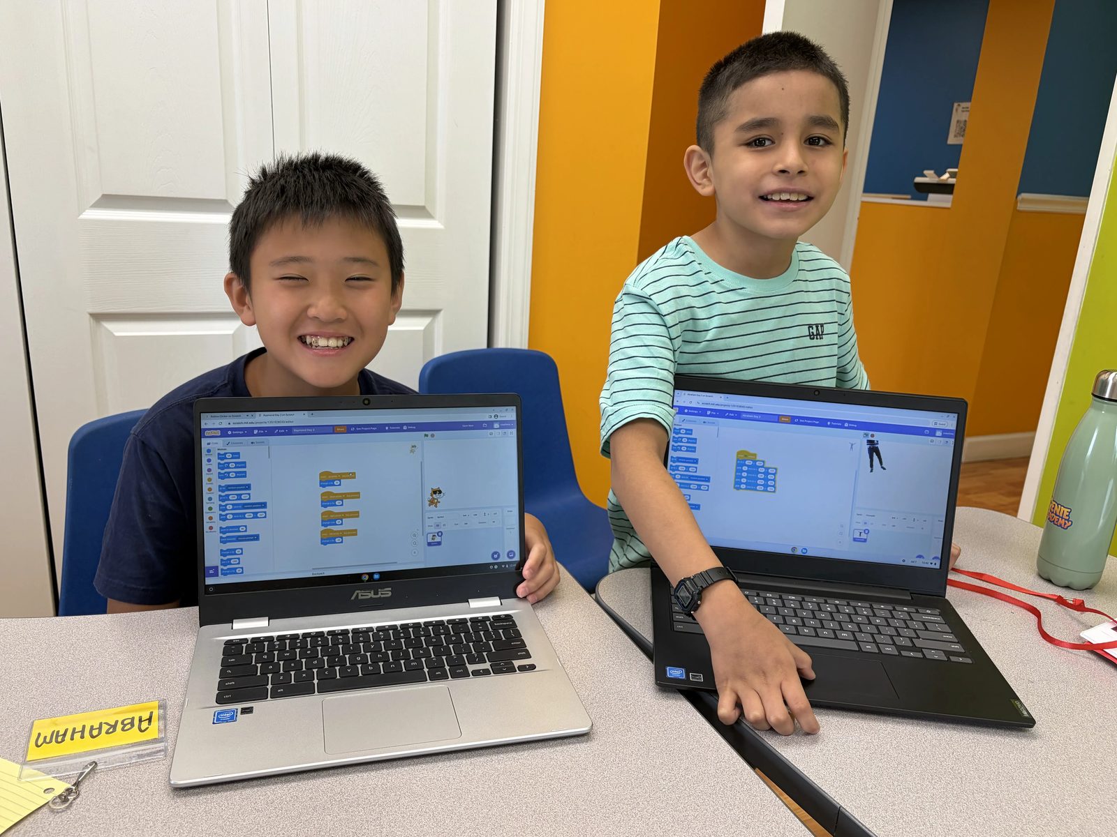 Two campers proudly showing off their Scratch coding projects on laptops at Genie Academy Summer Camp 2026